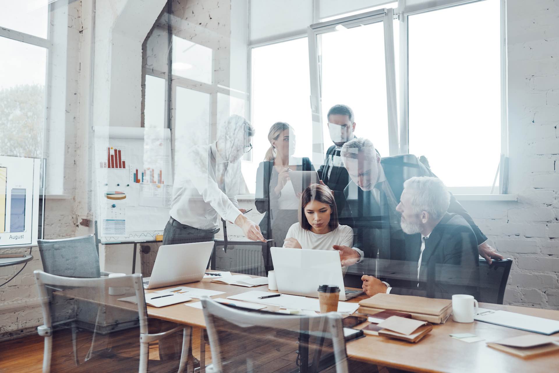 Self-motivated business team analyzing sales using modern technologies while having staff meeting in the board room