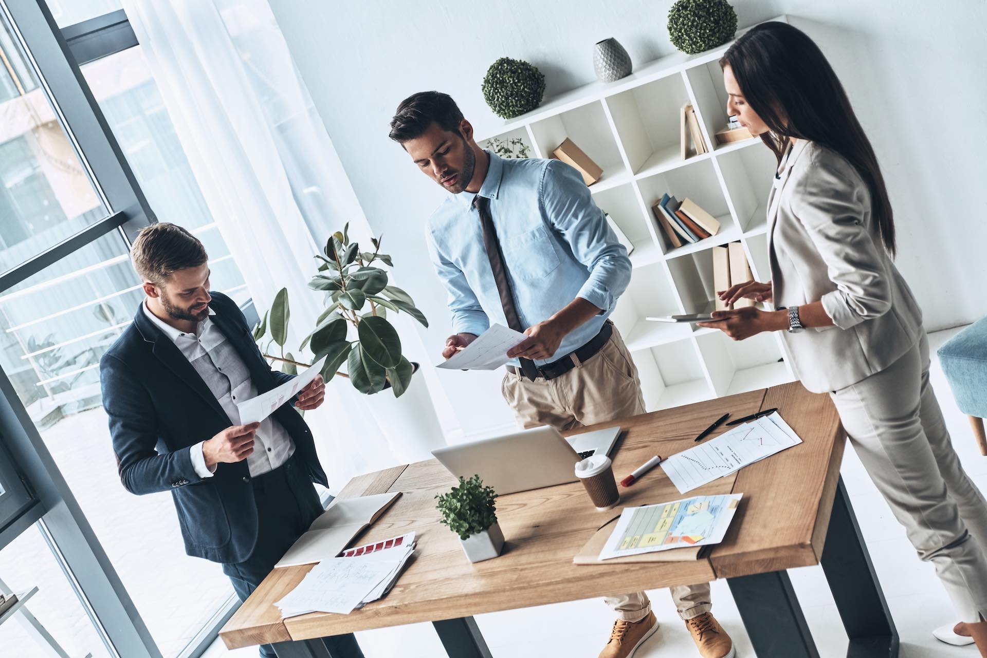 Successful business team. Top view of young modern people in smart casual wear discussing business while standing in the creative office