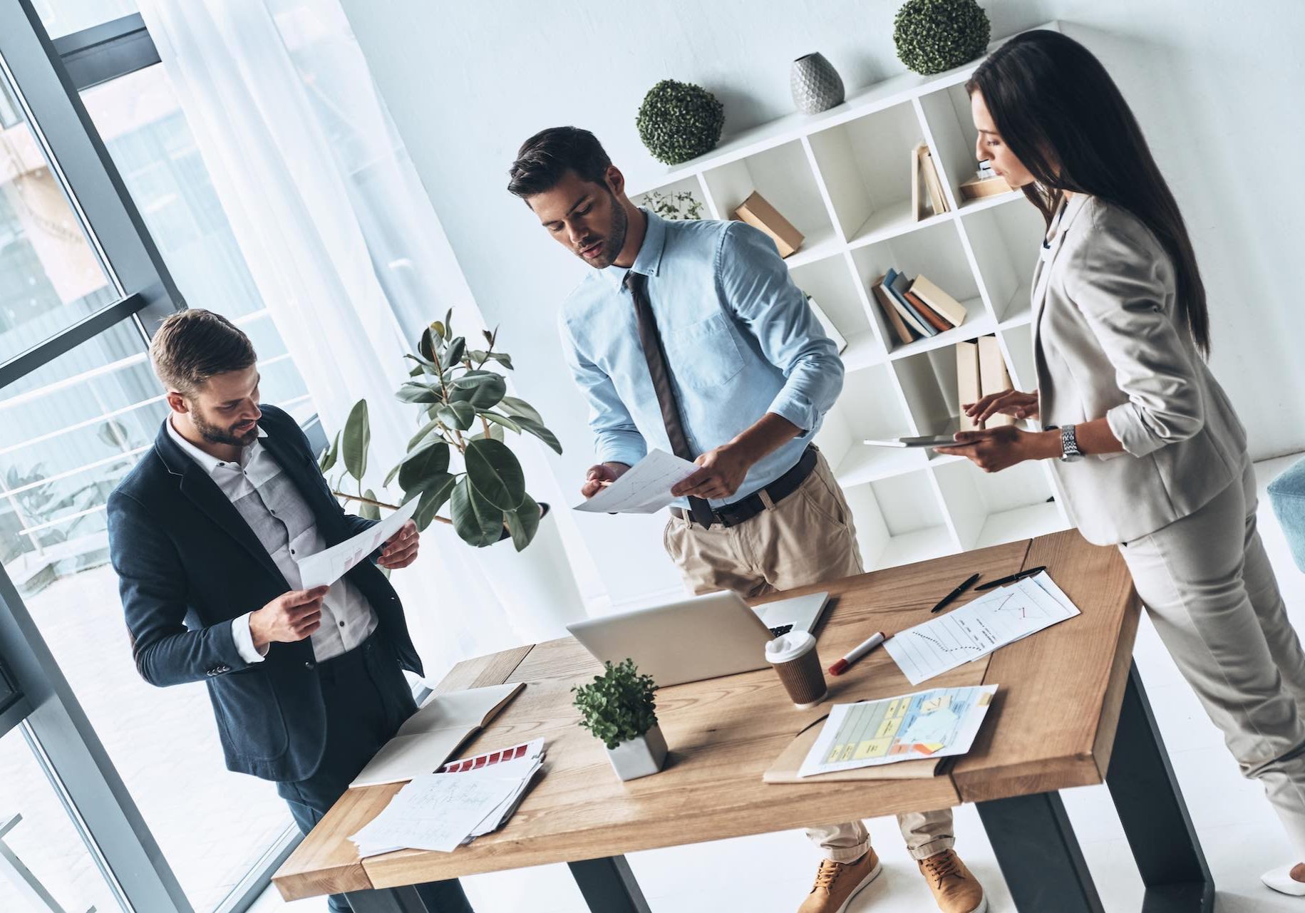 Successful business team. Top view of young modern people in smart casual wear discussing business while standing in the creative office